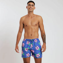 Load image into Gallery viewer, Breazies men swim shorts with pink hibiscus flower on a blue background - front view shown on a male model