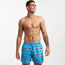 Load image into Gallery viewer, A smiling man stands shirtless against a plain backdrop wearing Breazies' luxury Adult Swim Shorts - Mr Fish in Bubblegum Blue. These quick-drying swim shorts feature a red and white shark pattern and are made from recycled polyester. With short hair and a left arm tattoo, he looks relaxed to the side.