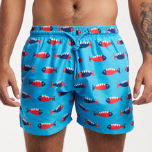 Load image into Gallery viewer, A man is in Breazies' Adult Swim Shorts - Mr Fish | Bubblegum Blue, featuring playful fish designs. Made from quick-drying recycled polyester, these shorts provide comfort and style on sun-soaked days by the water.