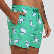 Load image into Gallery viewer, Breazies adult swim shorts with sharks on green background - side view with hand in pocket.