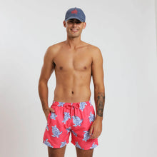 Load image into Gallery viewer, Breazies adult swim shorts with navy turtles on a coral red background - front view shown on a model with a cap on