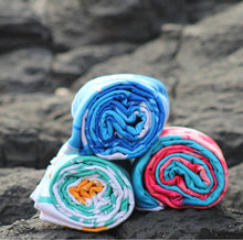 Load image into Gallery viewer, Three vibrant Beach Towels - Pine Palms by Bobums, made from recycled microfibre, in blue, teal, and pink hues are artistically arranged on dark textured rocks, with a blurred background highlighting the stylish display.