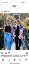 Load image into Gallery viewer, Two women smile while crossing a suspension bridge. One wears a colorful skirt and black top, and the other has Bobums' Beach Towel - Ice Cream Cones draped over her shoulders with black leggings and top. Lush greenery surrounds them.