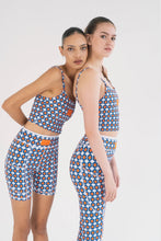 Load image into Gallery viewer, Two people in colorful athletic wear with a blue, orange, and white star pattern pose against a white background. One leans on the other's shoulder. Both wear matching tops and Koko Active's Shorty Shorts - The Court made from UV50 protection fabric with geometric patterns.