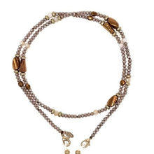 Load image into Gallery viewer, The Sichri Eyewear Strap - Livia Beige is a versatile sunglasses chain, featuring round and oblong beads in neutral brown, gray, and beige tones. Its design includes a metallic clasp and decorative charms for a blend of style and function.