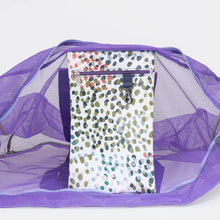 Load image into Gallery viewer, The Thandana Jumbo Lilac Mesh Beach Bag - Confetti is open, revealing a water-resistant pouch with a green, black, and pink polka dot pattern featuring a zipper and small hook at the top.