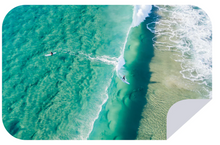 Load image into Gallery viewer, Aerial view of two surfers riding waves in turquoise ocean water near a sandy shoreline. The surfers are positioned one behind the other, with white surf trails visible in the clear sea. The image has a rounded corner on the bottom right, ideal for highlighting our quick-drying Bobums Extra Large Towel - Crystal Waters made from 100% recycled materials.