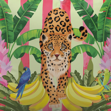 Load image into Gallery viewer, The Beach Bag - Lush Leopard Jungle by Natural Selection features a leopard surrounded by green banana leaves, bananas, a blue parrot on the left, and a green frog on the right. Pink vertical stripes provide a lively backdrop. It's crafted with durable poly canvas and comfortable cotton straps.