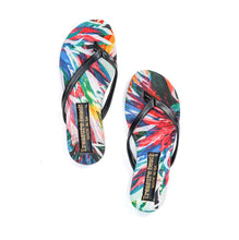 Load image into Gallery viewer, Treasure Beach "Tropical Black" flip flops feature colorful faux leather with a vibrant feather pattern in red, blue, and green. The black straps and footbeds display "Treasure Beach" in gold lettering. These comfort sandals are showcased side by side on a white background.