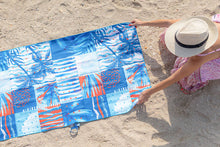 Load image into Gallery viewer, Woman with hat and her Microfibre towel with beach addict design and double sided pattern at La Mer beach.