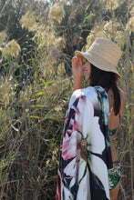 Load image into Gallery viewer, A woman in a straw hat and floral bikini stands in tall grass, smiling at the sun with the Bobums Beach Towel - Vintage Rose draped over her shoulder.