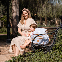 Load image into Gallery viewer, Mum sitting on a park bench with her little girl, laminated fabric Thandana diaper bag beside her.