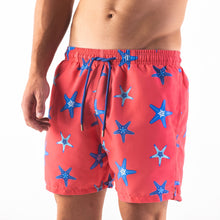 Load image into Gallery viewer, Man wearing starfish swim shorts, adults  - Blue starfish design on coral background