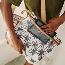Load image into Gallery viewer, A person in a green shirt slides a black tablet into the transparent outer pocket of the Thandana iPad Clear Pouch - Linear Preppy.
