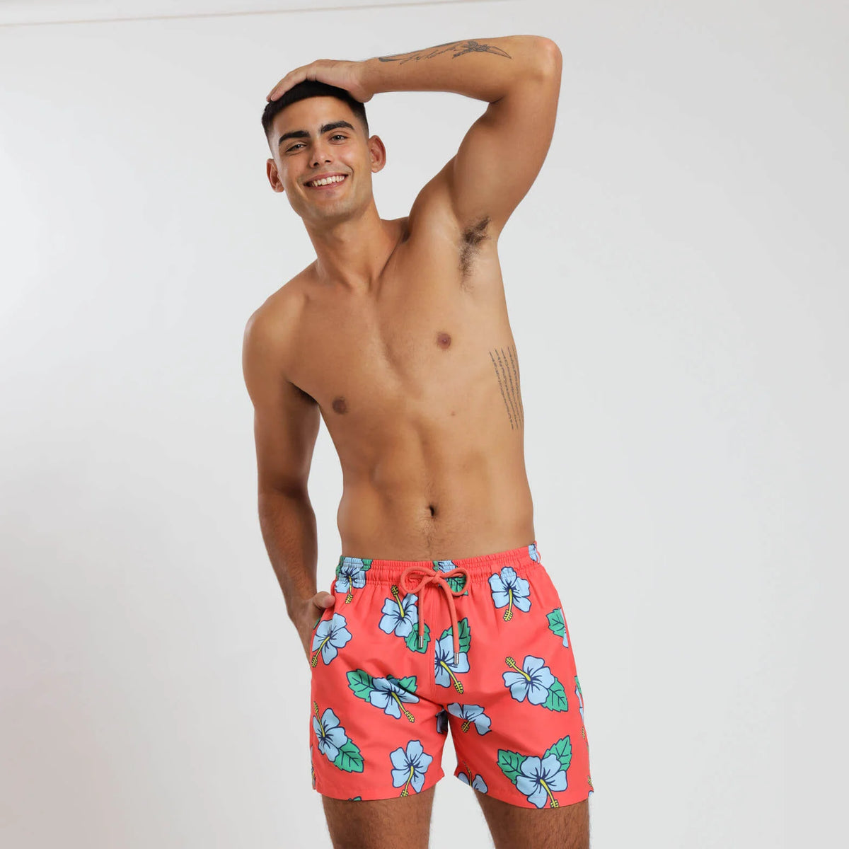 Breazies swim shorts for adults - hibiscus flower on orange background - front view shown on  model with hand on his head