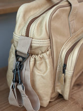 Load image into Gallery viewer, Thandana genuine leather baby nappy bag with a strap and bottle pocket on a wooden surface.
