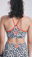 Load image into Gallery viewer, Person wearing a leopard print sports bra and shorts with red  accents on a plain background
