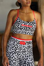 Load image into Gallery viewer, A person wearing Koko Active’s Extra Shorty Shorts - Step Up, with leopard print and red accents, exemplifies the brand&#39;s blend of style and sustainability. Ethically produced, this ensemble shines under natural light indoors, merging fashion with conscience effortlessly.
