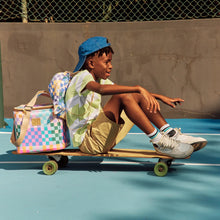 Load image into Gallery viewer, Child sitting on a skateboard on a tennis court with a colorful cooler bag next to him and a Thandana drawstring bag on his back.
