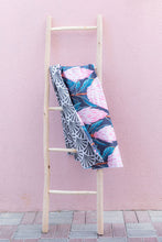 Load image into Gallery viewer, Bobums UAE Microfibre beach towel with Pink Protea design on ladder against pink wall at Tania&#39;s Tea House
