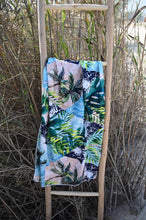 Load image into Gallery viewer, Bobums UAE Microfibre beach towel with Geo Palm design on ladder in front of grass at Black Palace Beach
