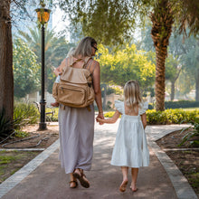 Load image into Gallery viewer, Women carrying Thandana nappy backpacks while walking with their kids in the park.

