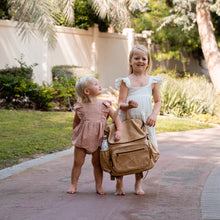 Load image into Gallery viewer, Thandana Hazelnut Leather Baby Nappy Backpack carried by two kids walking in the park.
