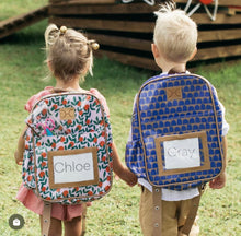 Load image into Gallery viewer, Thandana school backpacks worn by two children. The backpacks made with laminated fabric with genuine leather trims, water-resistant interior, and adjustable straps for children.
